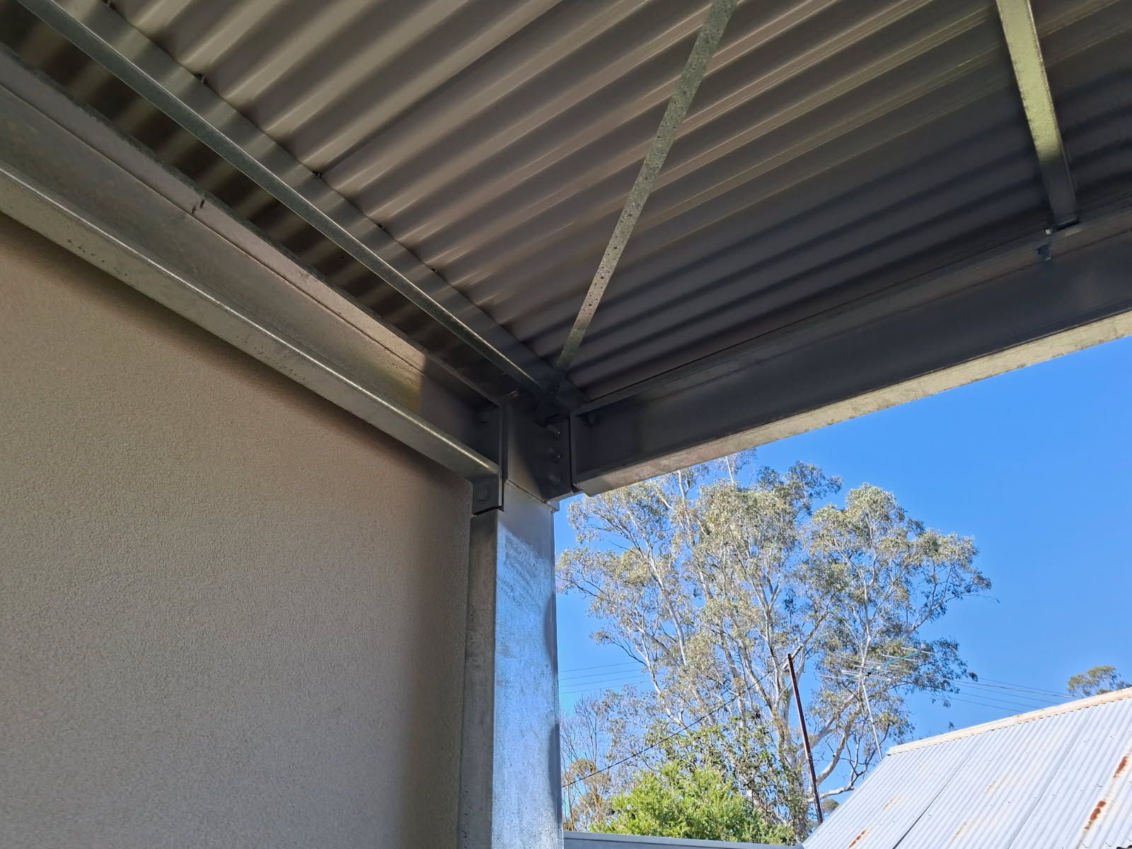 Close-up of a steel post-and-beam connection on the Tanunda pergola against a rendered wall